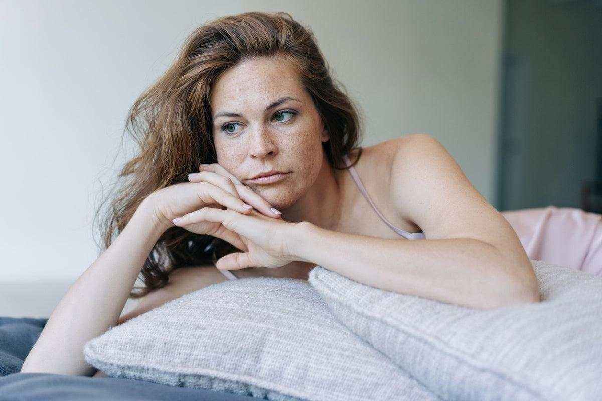Navigating Genitourinary and Sexual Changes in Menopause - woman resting on bed looking thoughtful, hormonal changes and intimate discomfort