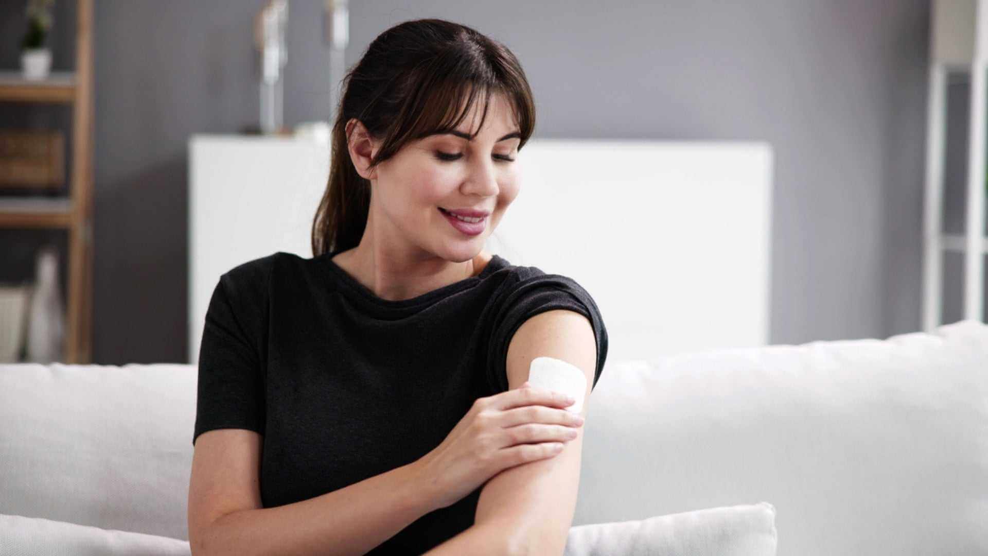 Alt Tag: Woman applying hormone patch on upper arm at home, Menopausal Hormone Therapy treatment for menopause symptom relief