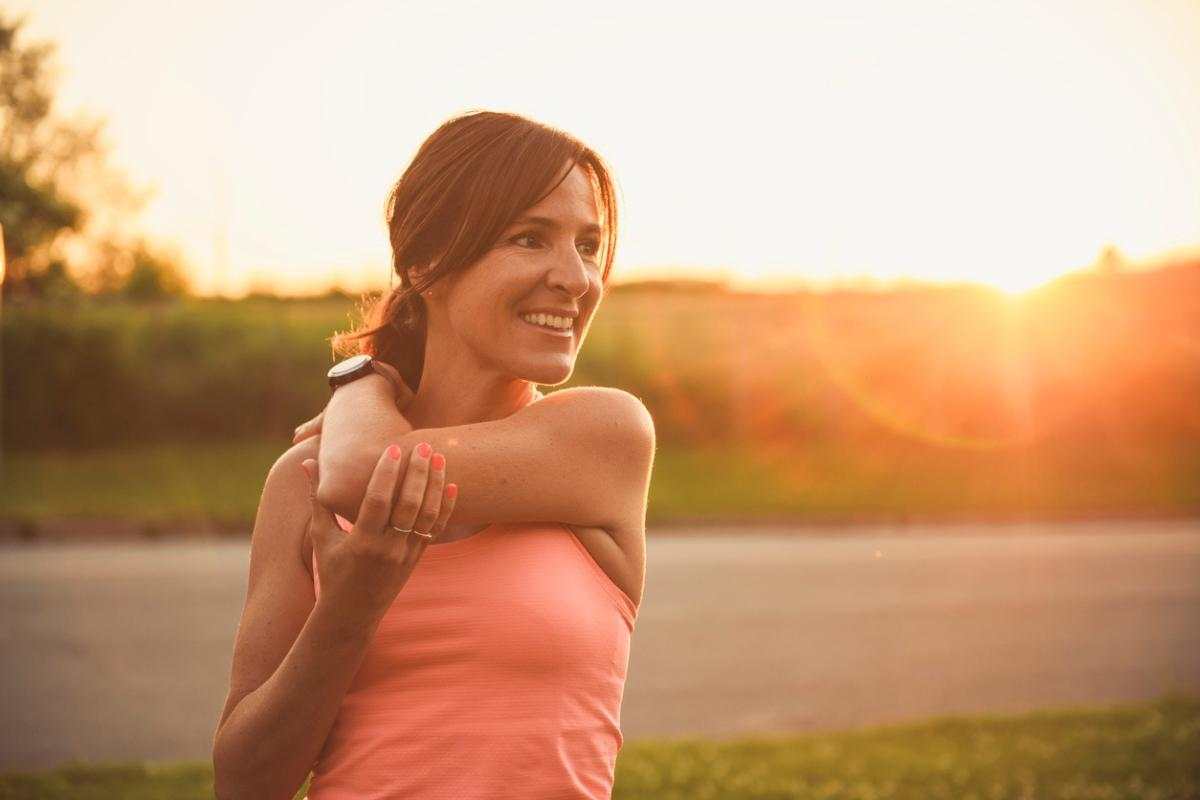 Woman stretching outdoors at sunset promoting exercise and skin health benefits