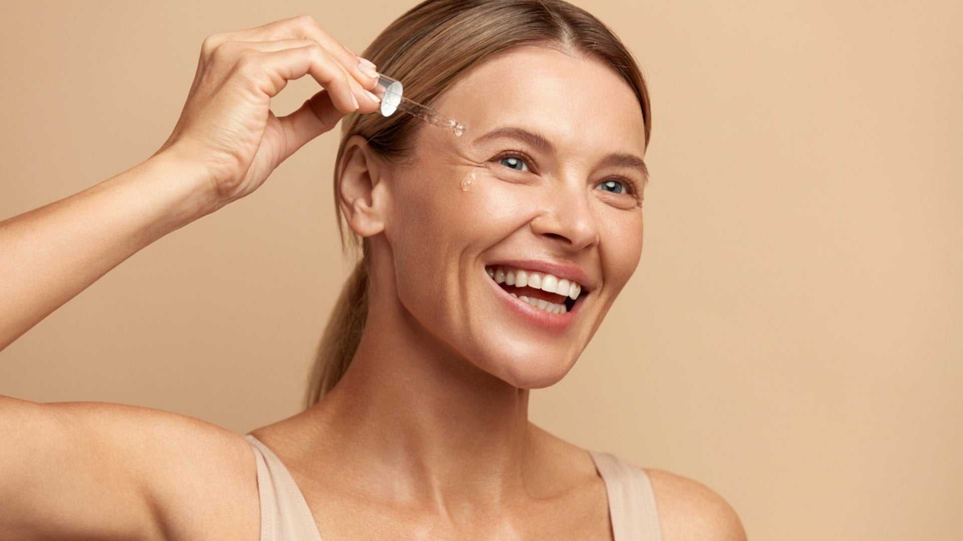 Happy woman applying collagen serum to her face for radiant and youthful skin care routine