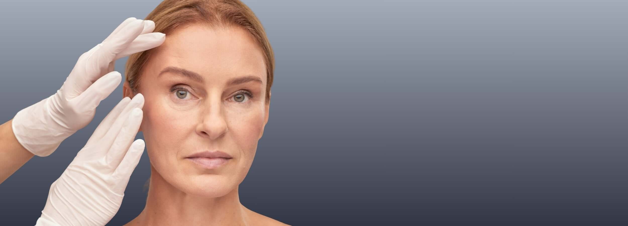 Comparing Radiesse and Sculptra: Which Is Better? doctor with gloved hands assessing woman’s face for dermal filler treatment