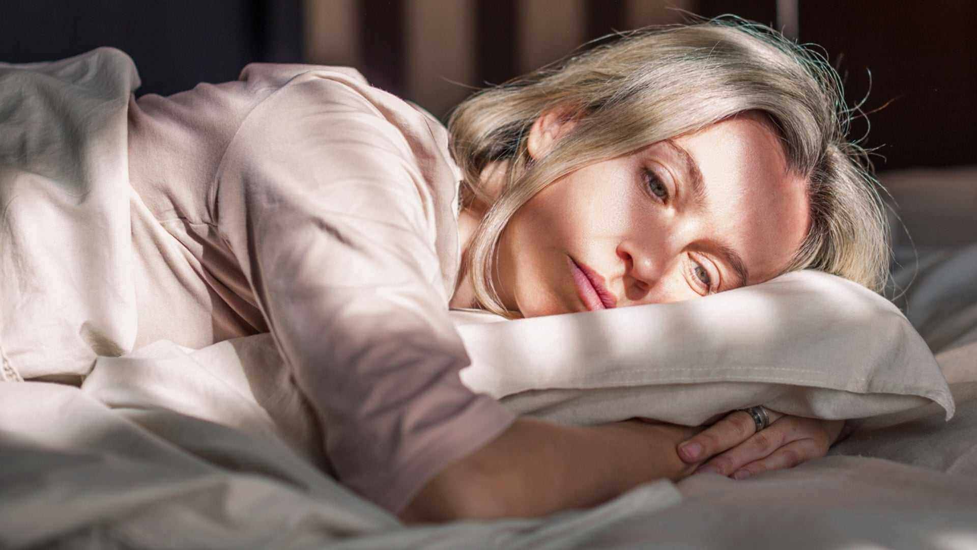 Alt Tag: Menopause and Your Skin: Understanding and Managing Changes—woman lying awake in bed, fatigue and sleep disruption symptoms