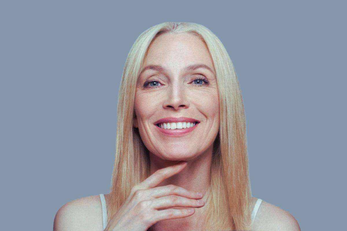 smiling middle-aged woman showcasing smooth skin with reduced smile lines for fillers for smile lines article