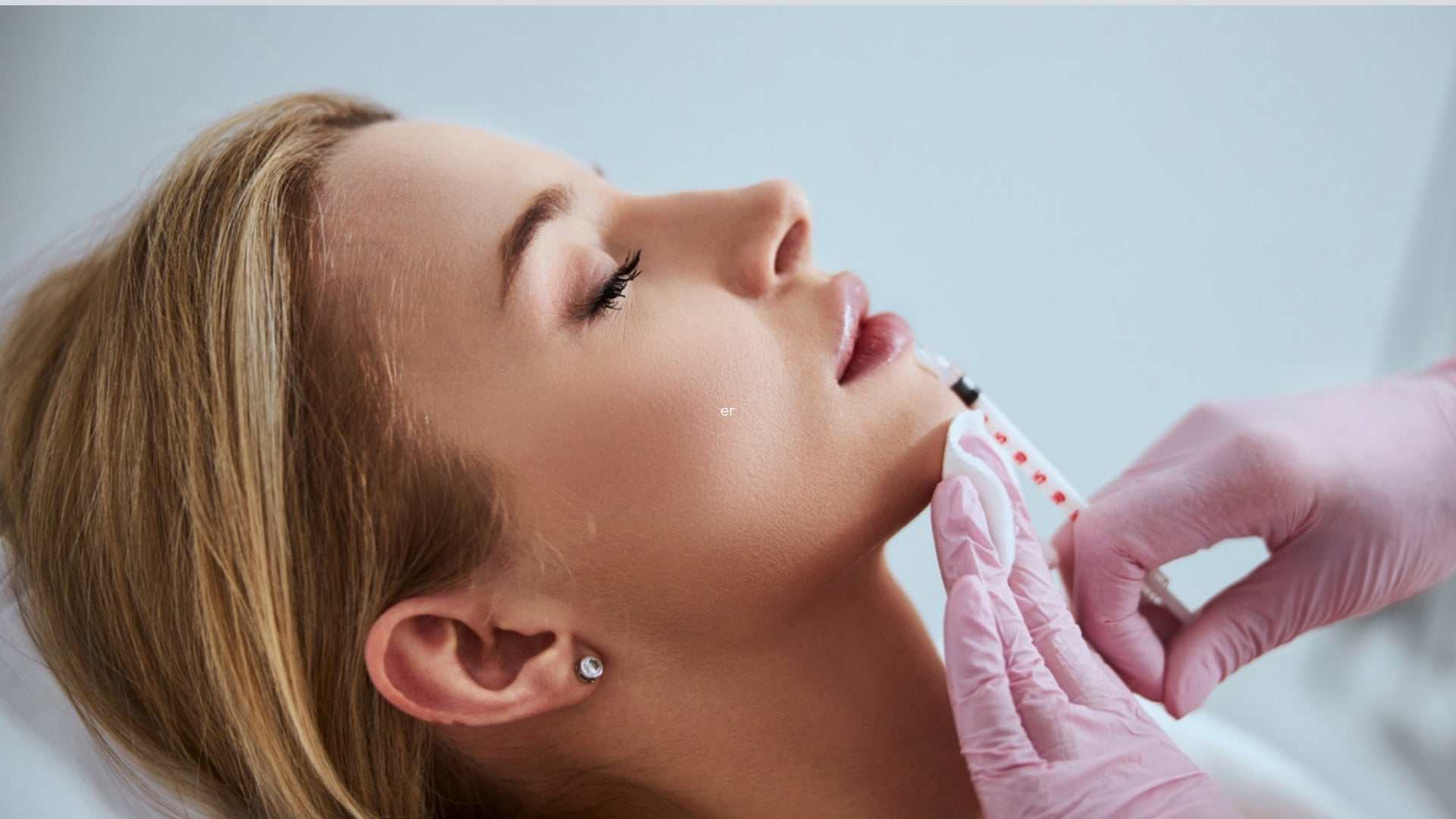 Woman receiving facial filler injection treatment by professional in medical gloves