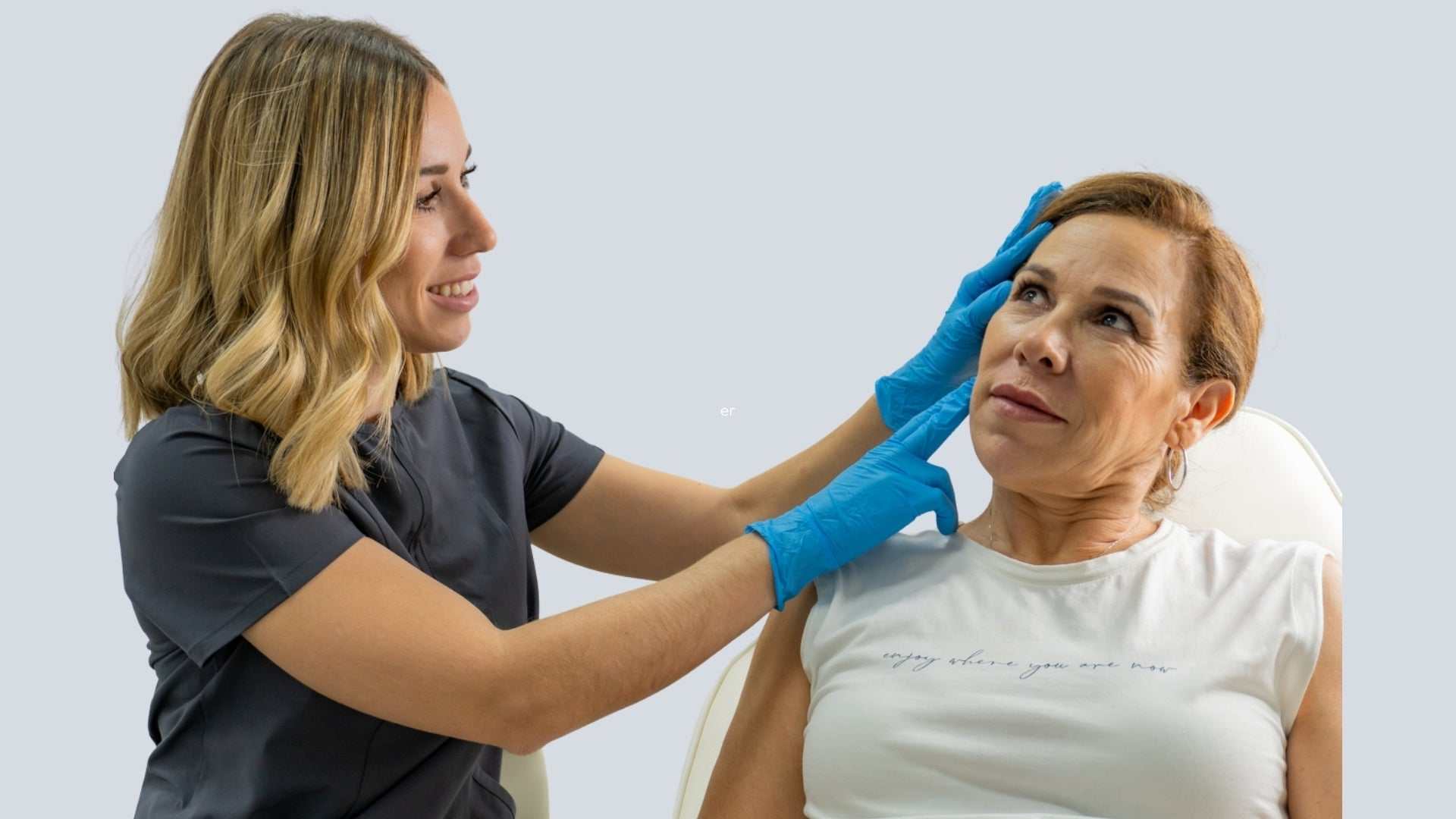 Medical professional wearing gloves examining middle-aged woman’s jaw area for masseter Botox treatment for TMJ relief.