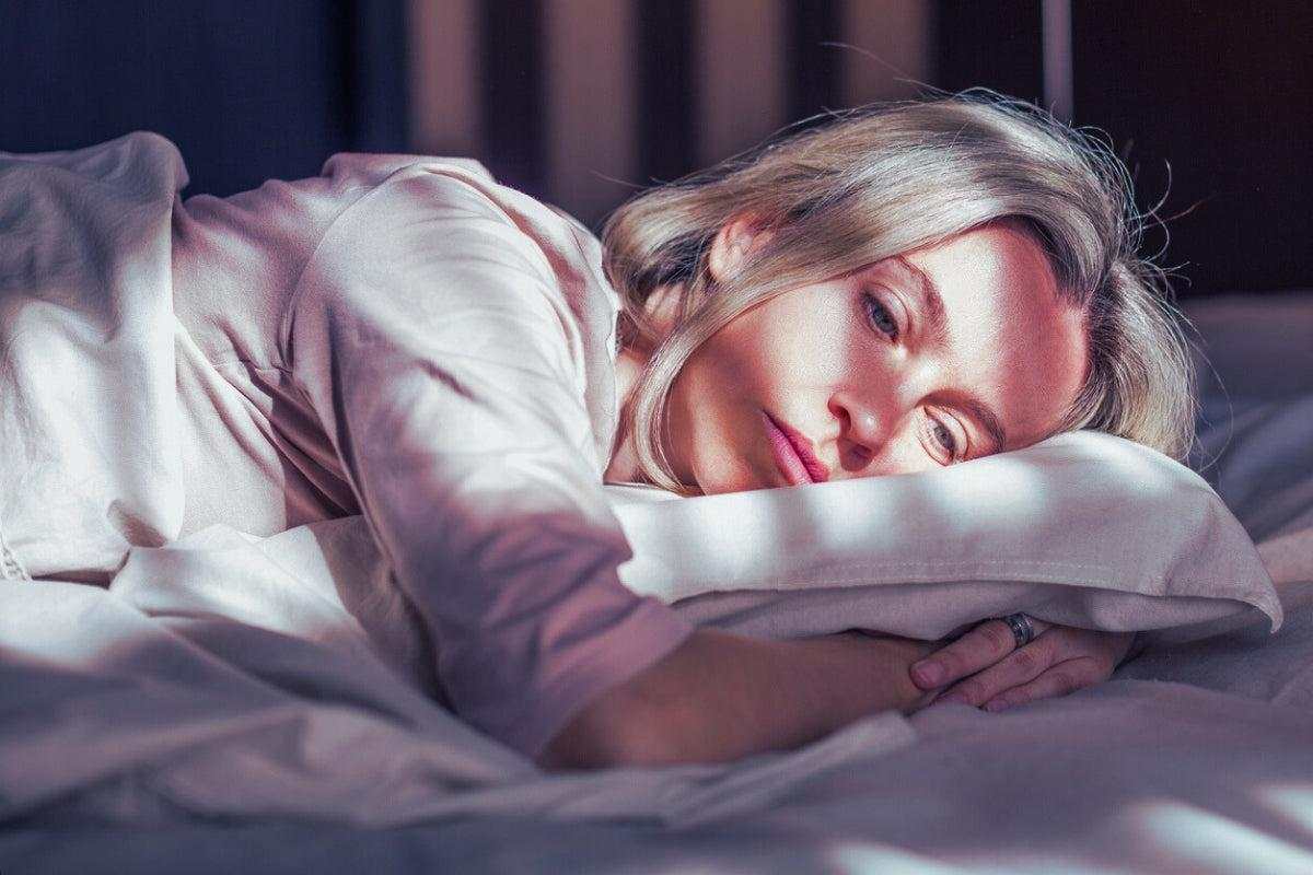 Middle-aged woman lying awake in bed struggling with menopause-related sleep disruption at night