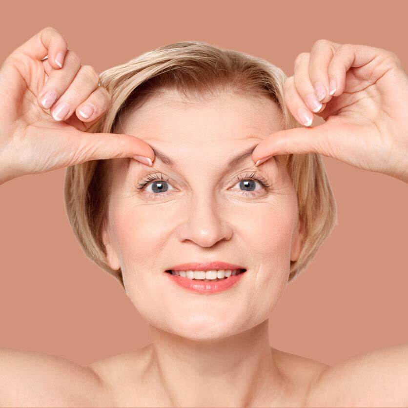 Mature woman lifts her eyebrows smiling to demonstrate Botox - brow lift