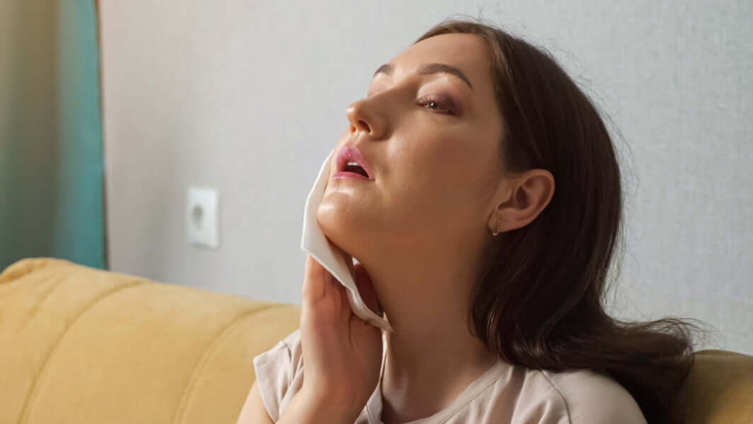 Woman applying a facial mask on her face with a neutral background