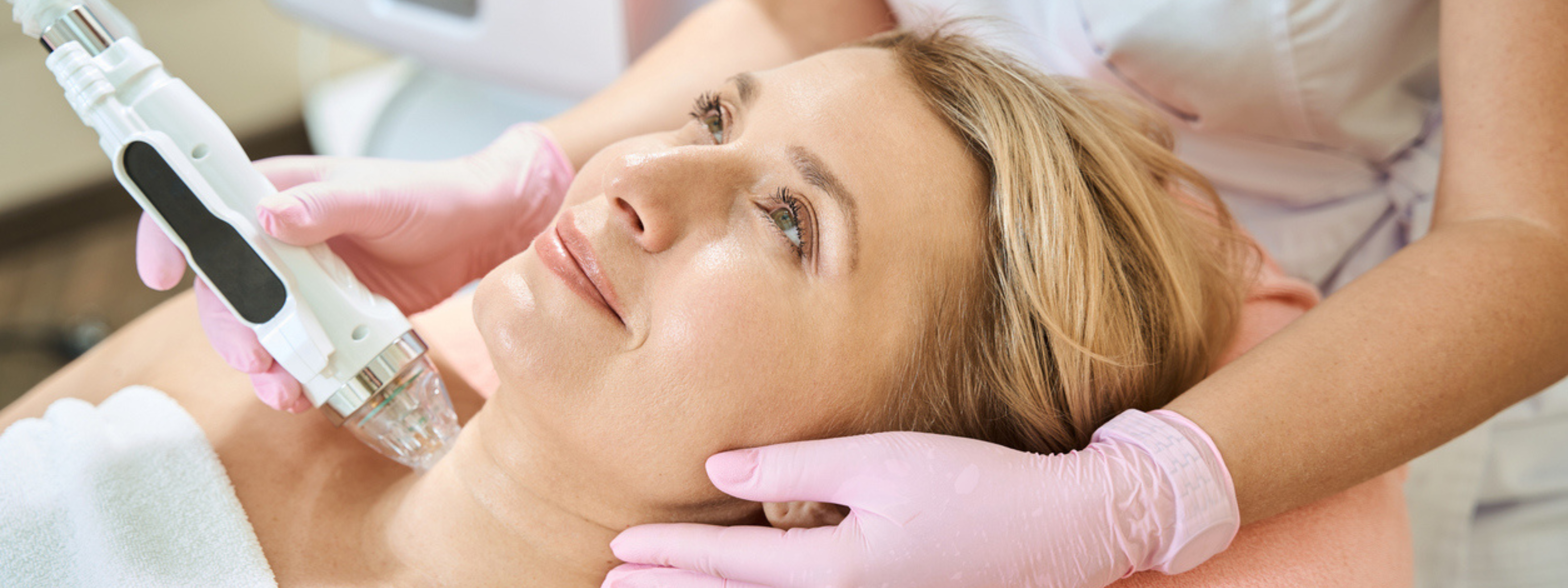 Woman receiving a facial treatment with a device from a professional.