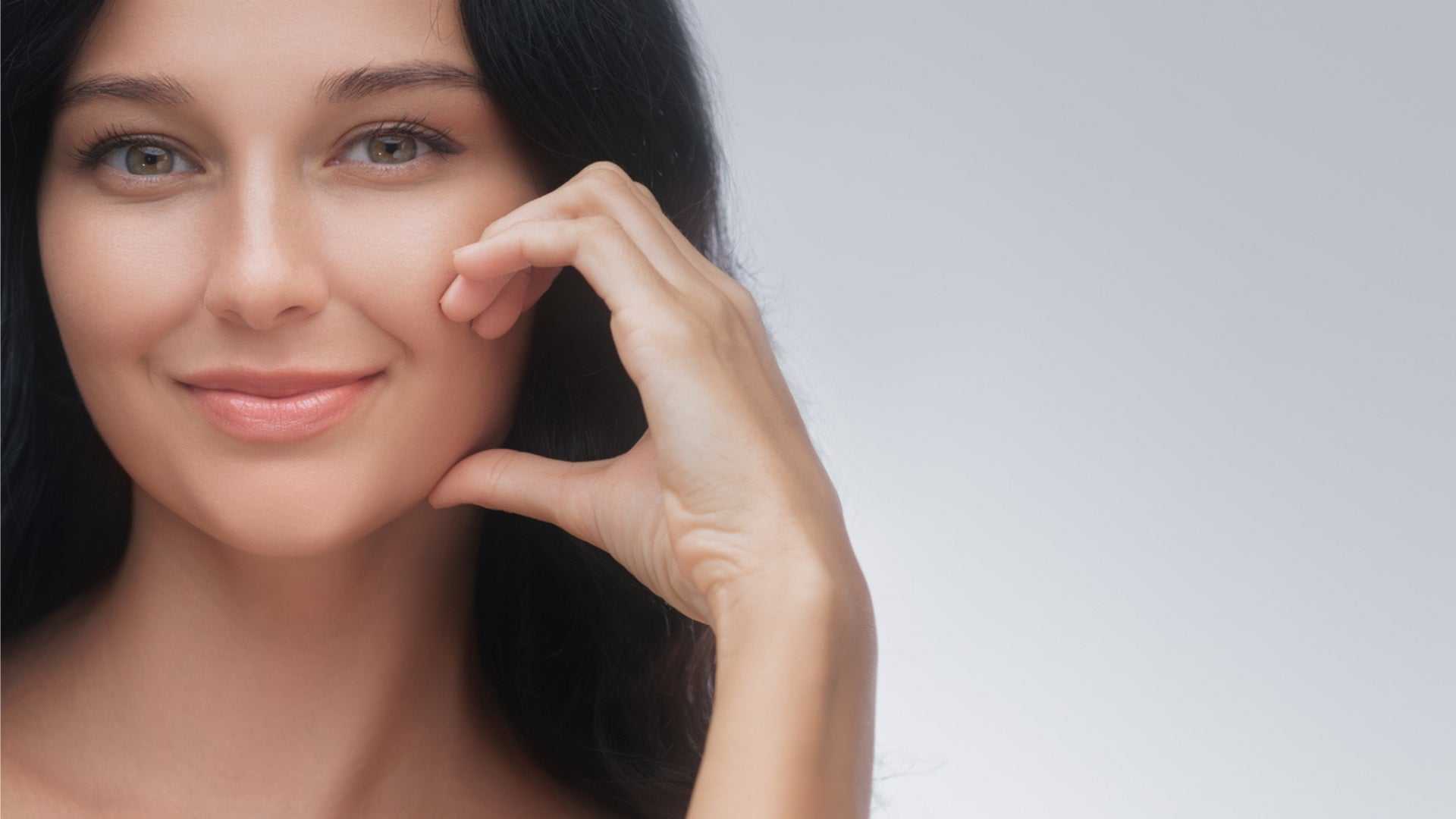 smiling woman with clear skin touching her face representing laser clinics near me and skin wellness