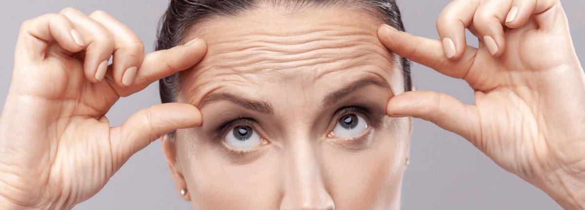 How Many Botox Units for Forehead? woman lifting forehead skin showing wrinkles and expression lines before Botox treatment