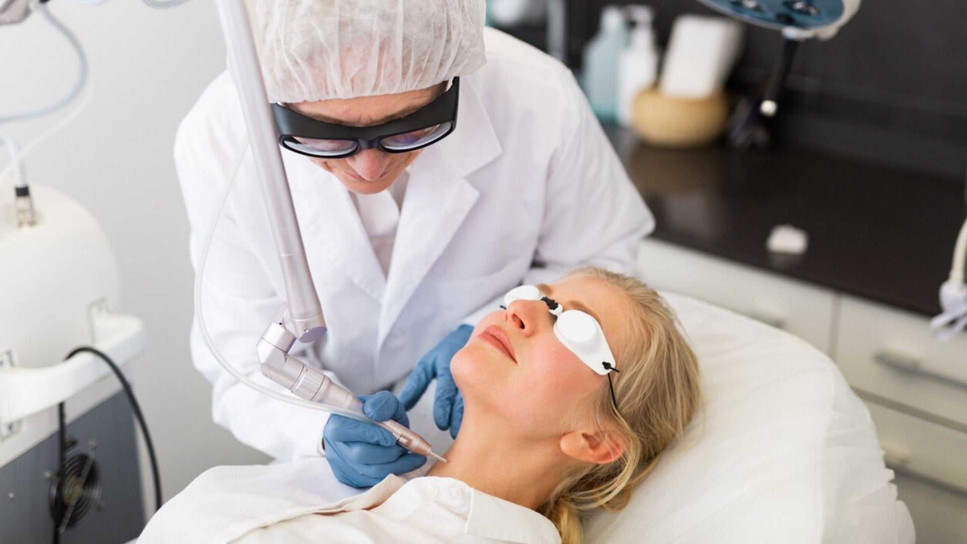 Woman receiving laser skin resurfacing treatment from a medical professional in a clinical setting