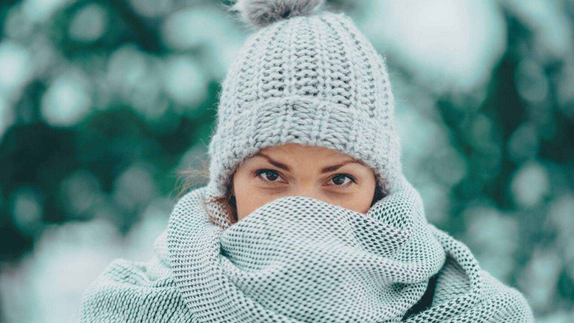 woman wearing knitted hat and scarf outdoors in winter cold weather for seasonal skin care routine