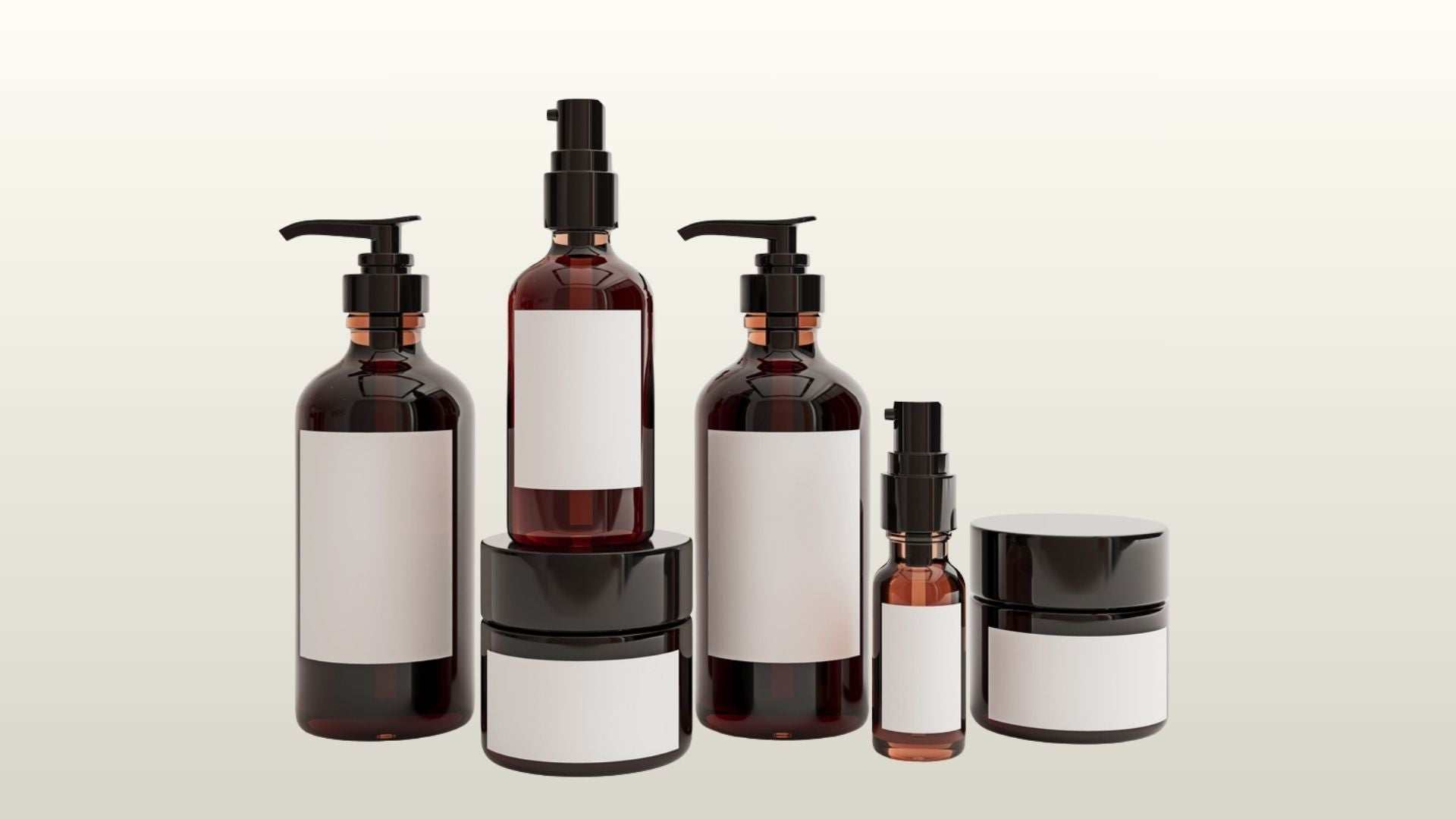 Set of amber glass skincare bottles and jars with blank white labels on a neutral background, representing skin care sets.