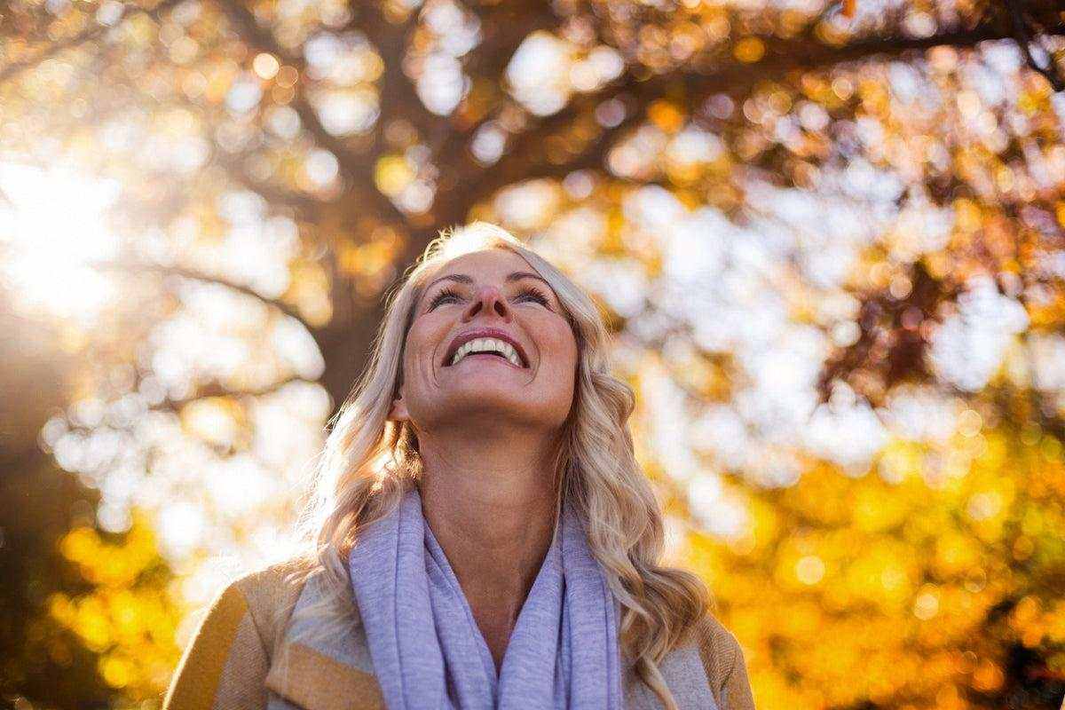 Happy woman enjoying sunlight outdoors in autumn, symbolizing improved sleep quality and understanding insomnia