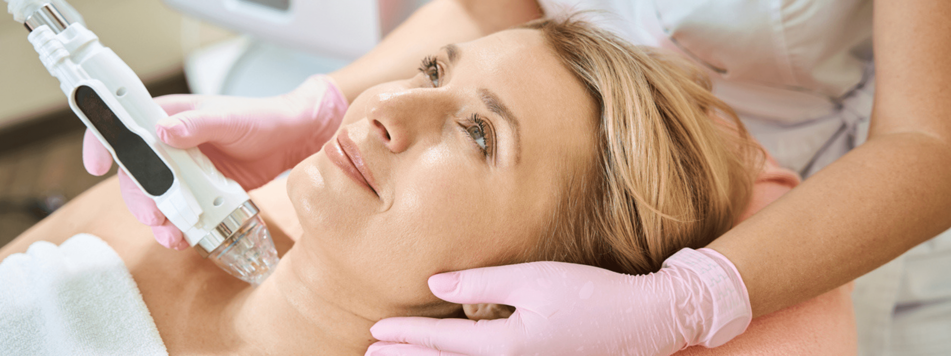 Woman receiving a facial treatment with a device from a professional.