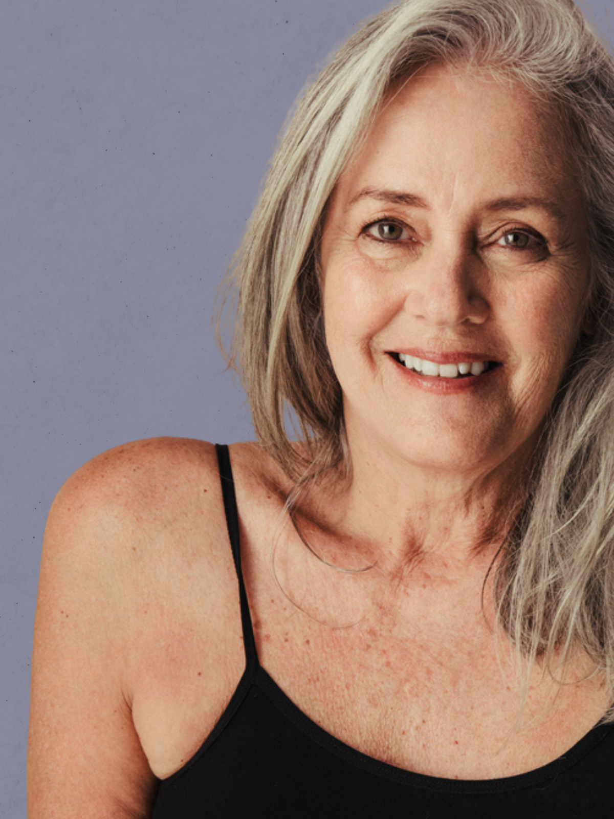 Woman with gray hair smiling against a plain background. Medical pigmentation treatment program for dark spots, sun damage, and uneven skin tone - physician-supervised clinical treatments at Merrion Medical Aesthetics Oakville
