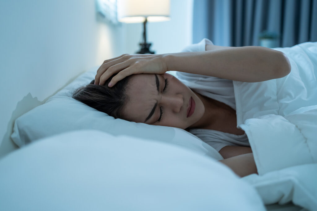 Woman lying in bed suffering from a headache